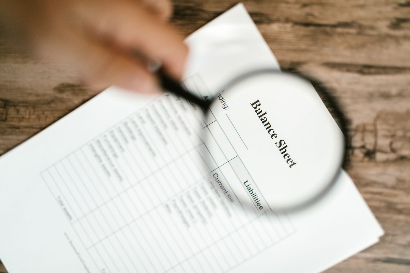 Close-up of a balance sheet under a magnifying glass, representing audited financial statements review for UAE Corporate Tax