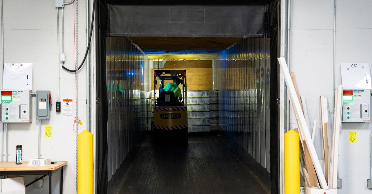 Forklift unloading goods at an industrial warehouse loading dock, representing UAE Free Zone manufacturing and warehousing qualifying activities under Ministerial Decision No. 229