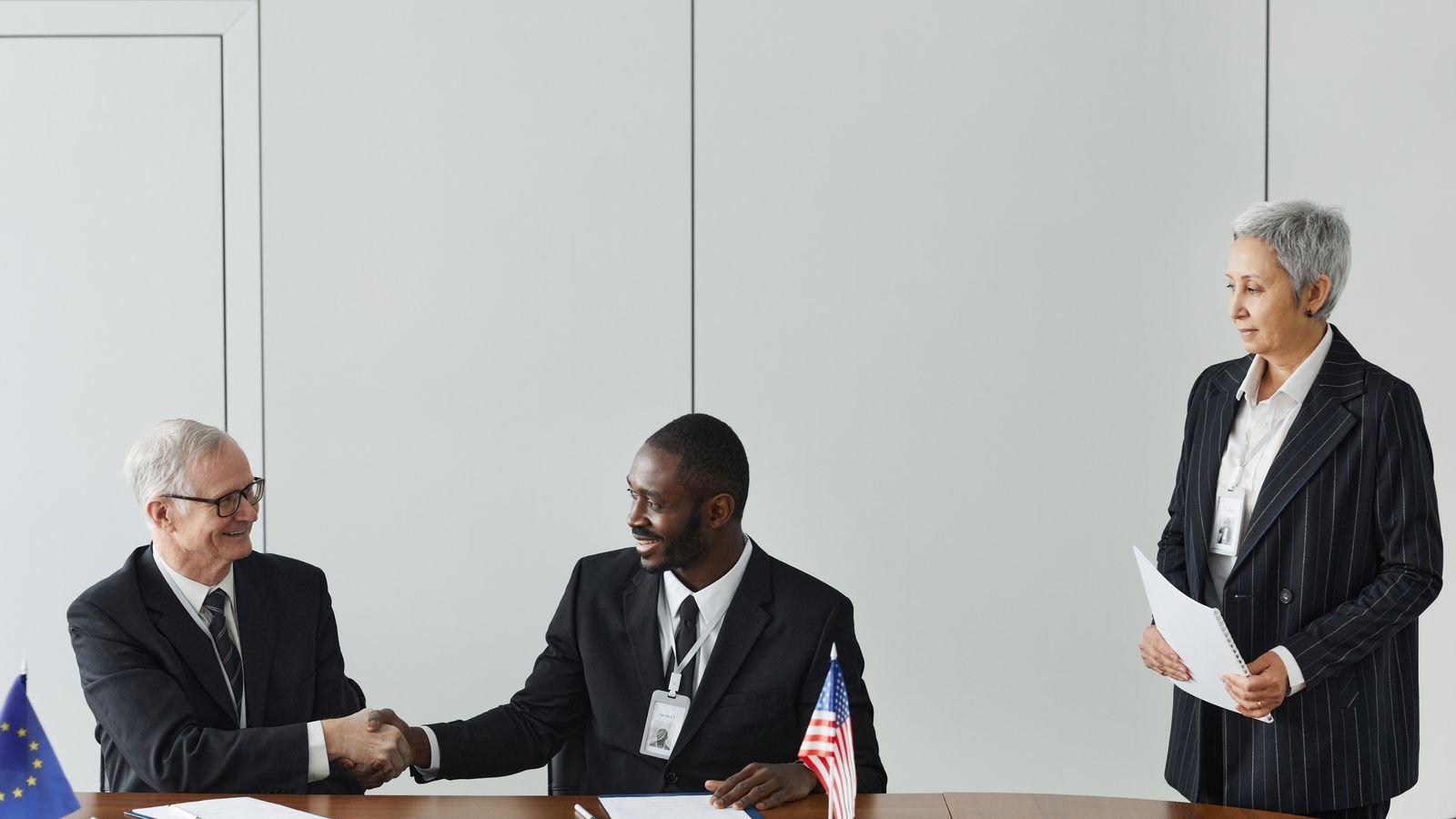 Two business professionals shaking hands over a signed international agreement, representing UAE double tax treaty relief between companies
