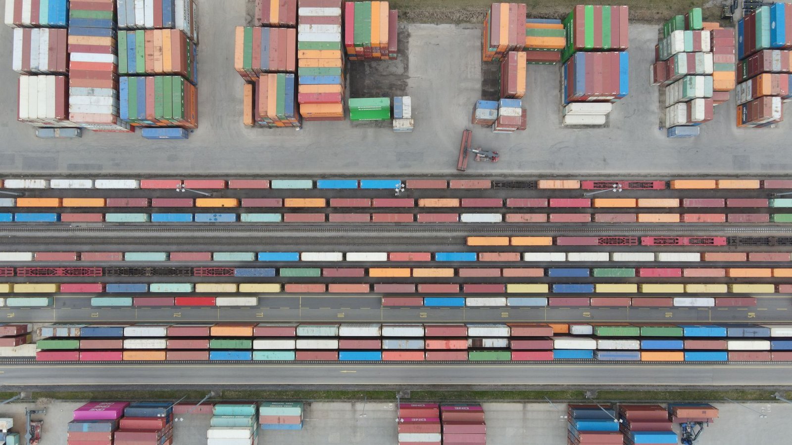 Aerial view of shipping containers and cranes at an industrial port, representing KEZAD free zone logistics and trading operations in Abu Dhabi