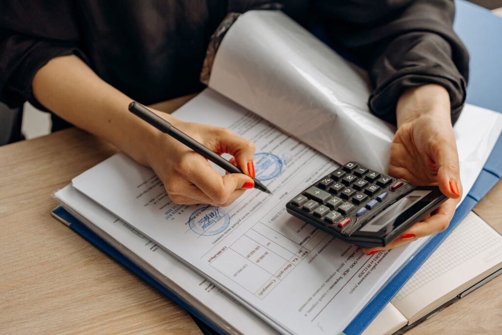 An accountant using a calculator and signing paperwork while reviewing figures, illustrating cash basis versus accrual basis accounting for UAE corporate tax