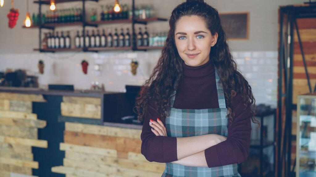 Confident café owner standing inside a cozy coffee shop, representing opening a restaurant or cafeteria in Dubai