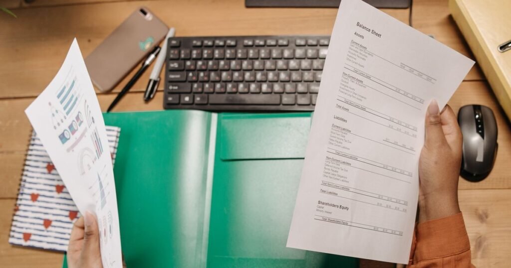 Hands holding a balance sheet that lists intangible assets next to a chart report, illustrating UAE Corporate Tax on goodwill and intangibles