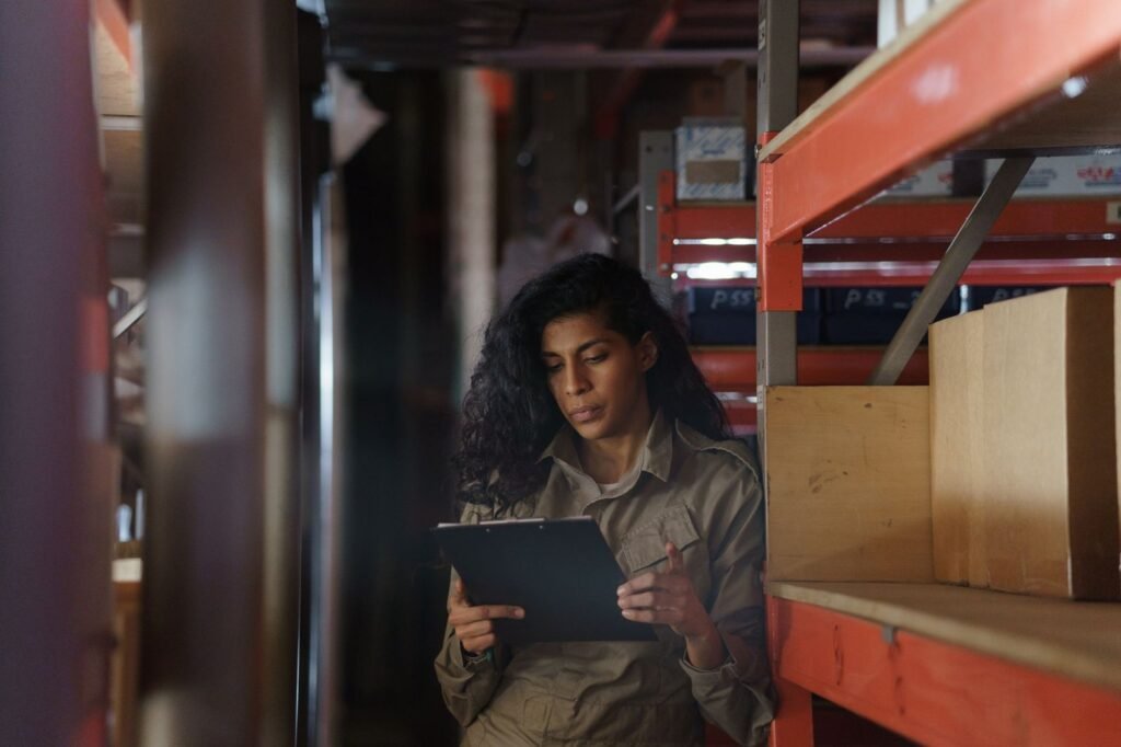 Woman with a clipboard taking inventory in a warehouse, illustrating stock valuation and write-downs under UAE Corporate Tax