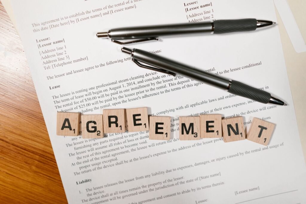 Agreement document with scrabble tiles and pens on a desk, illustrating lease and rent costs for UAE corporate tax
