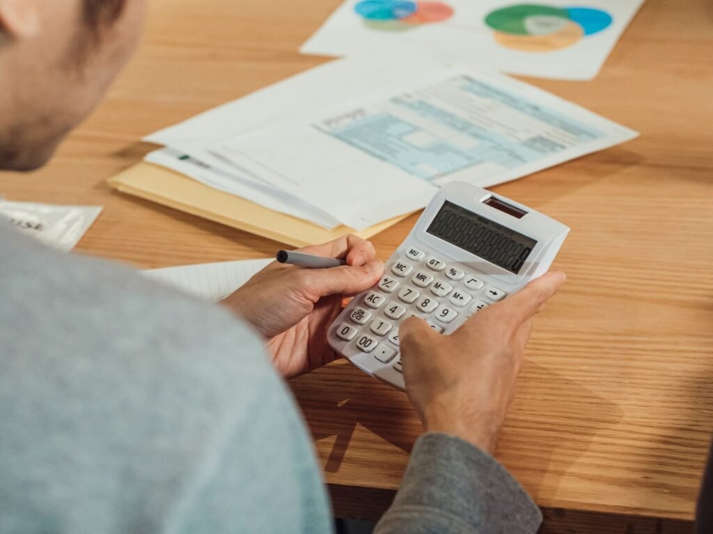 Person using a calculator beside finance documents on a desk, representing input VAT recovery on employee expenses in the UAE