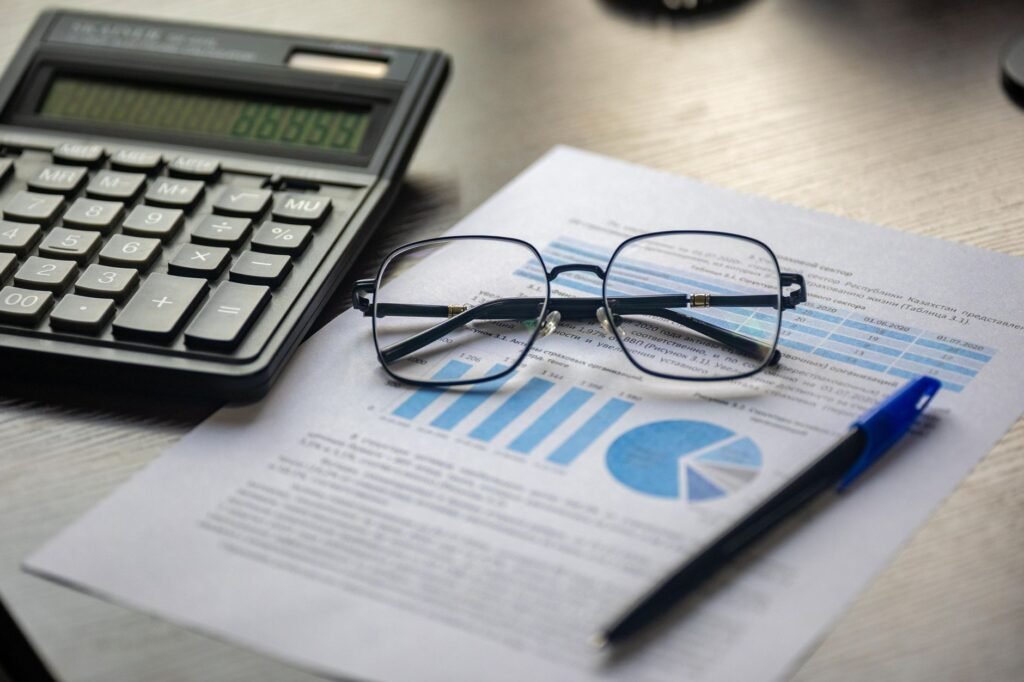 Calculator, reading glasses and a printed financial report on a desk, representing UAE VAT tax invoices and credit notes